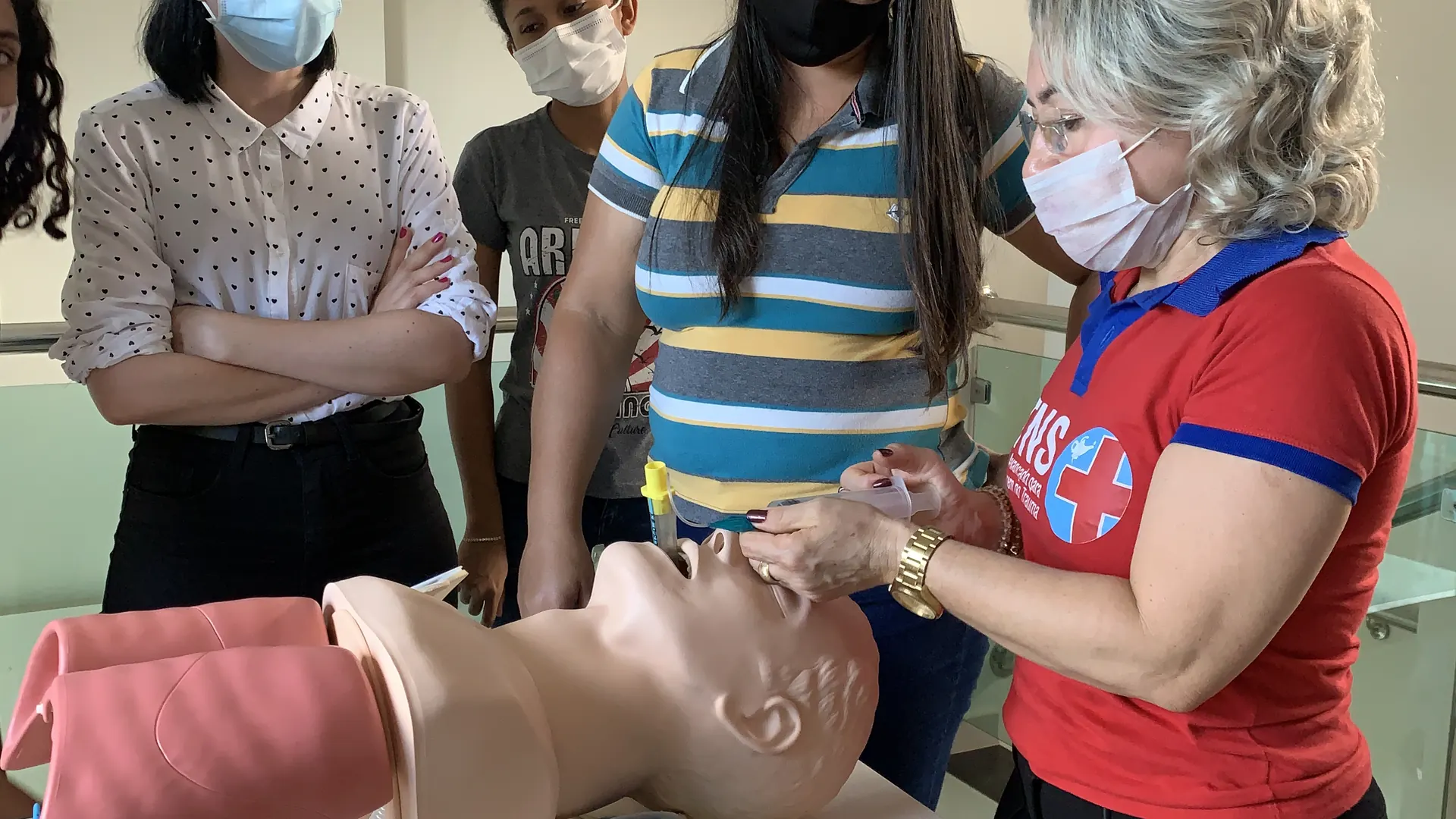 Instrutora demonstra manejo de via aérea em manequim, com a turma observando